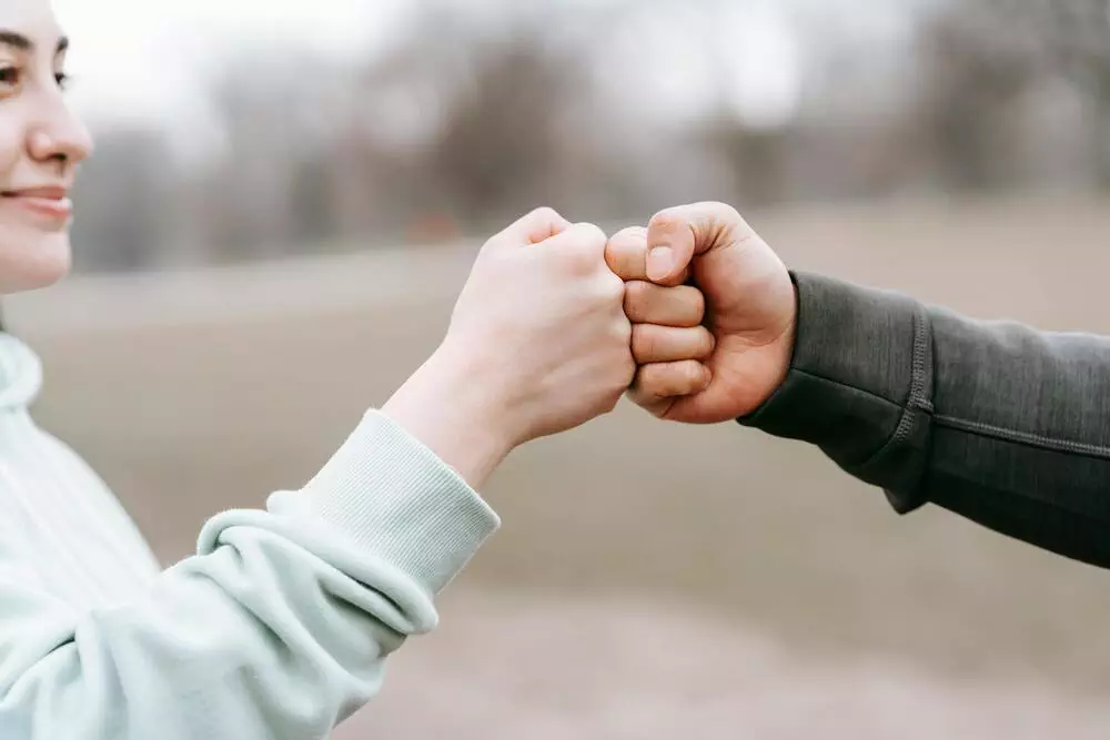 Two people sharing a fist bump outdoors, signifying unity and support.