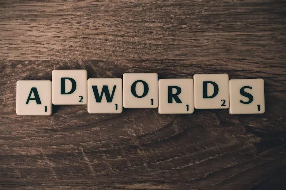 Scrabble tiles spell out ADWORDS on a wooden background.