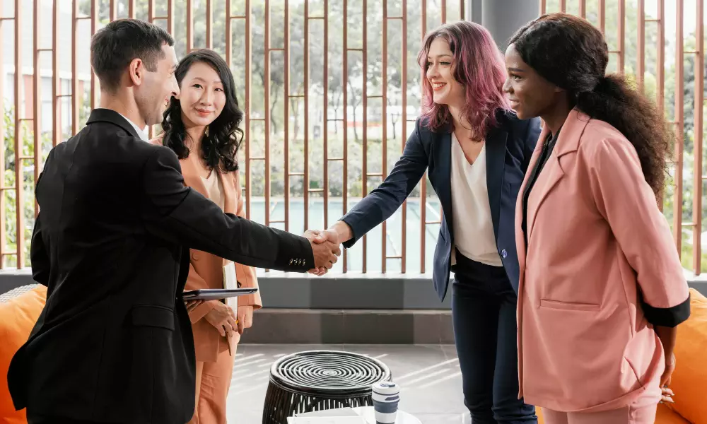 Diverse business team having a meeting, two women shaking hands.